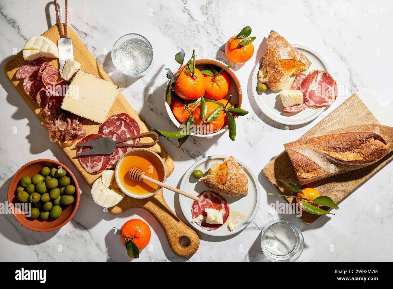 Tagliere di salumi con olive, salumi, formaggio, pane e arance su sfondo di marmo Foto Stock