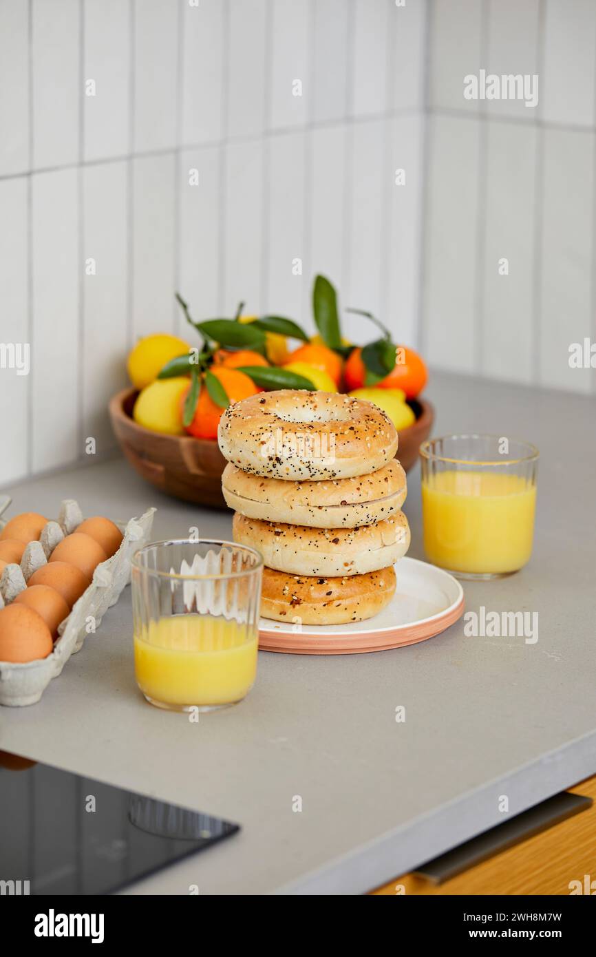 Bagel mattutini in cucina con succo d'arancia, uova e agrumi Foto Stock