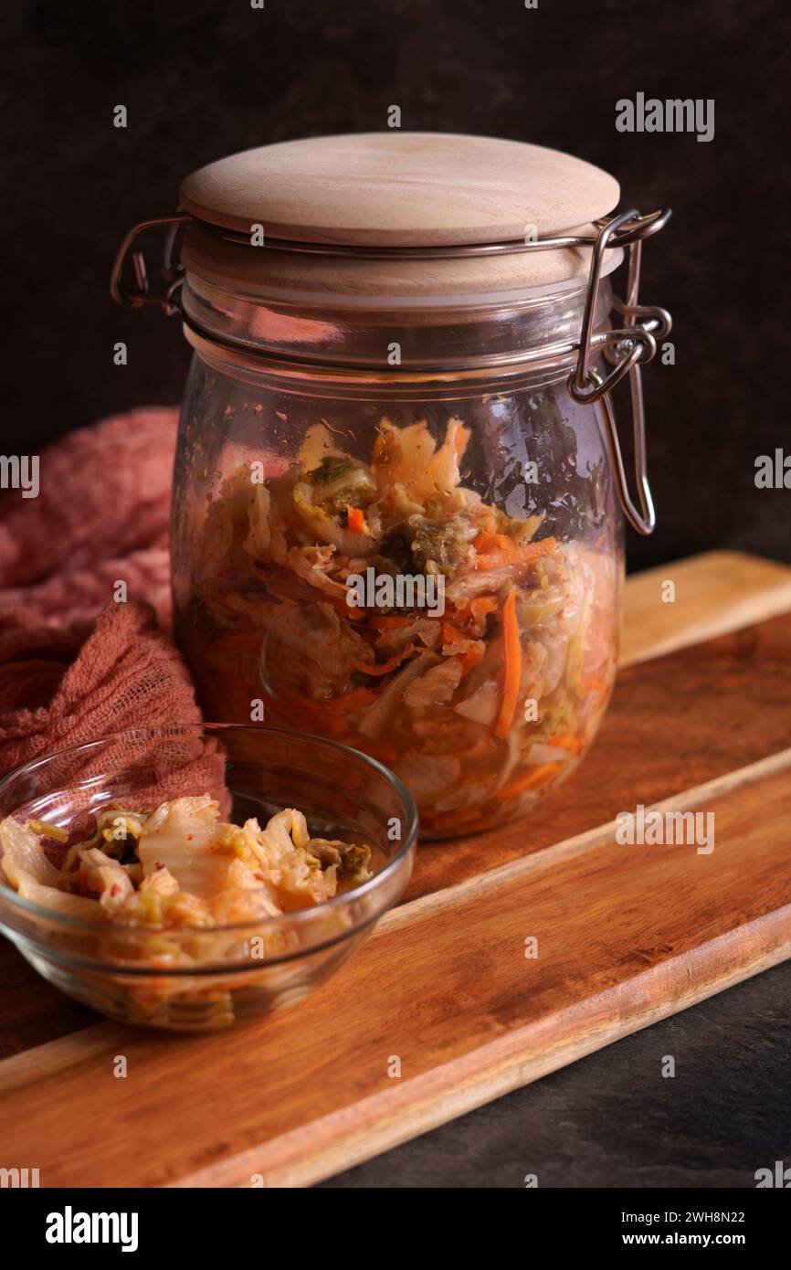 Kimchi in sano stile coreano probiotico in vaso di vetro primo piano su uno sfondo scuro. Foto Stock