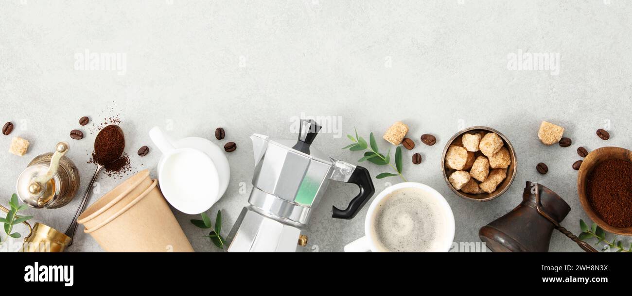 Adagiati in piano con moka pot, tazza espresso, caffè macinato, latte, zucchero e chicchi di caffè su sfondo grigio in cemento. Spennellare con l'ingrediente per preparare il caffè Foto Stock