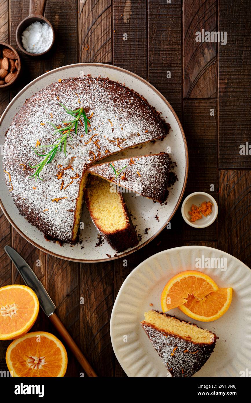 Torta di mandorle arancioni a fette su sfondo di legno Foto Stock