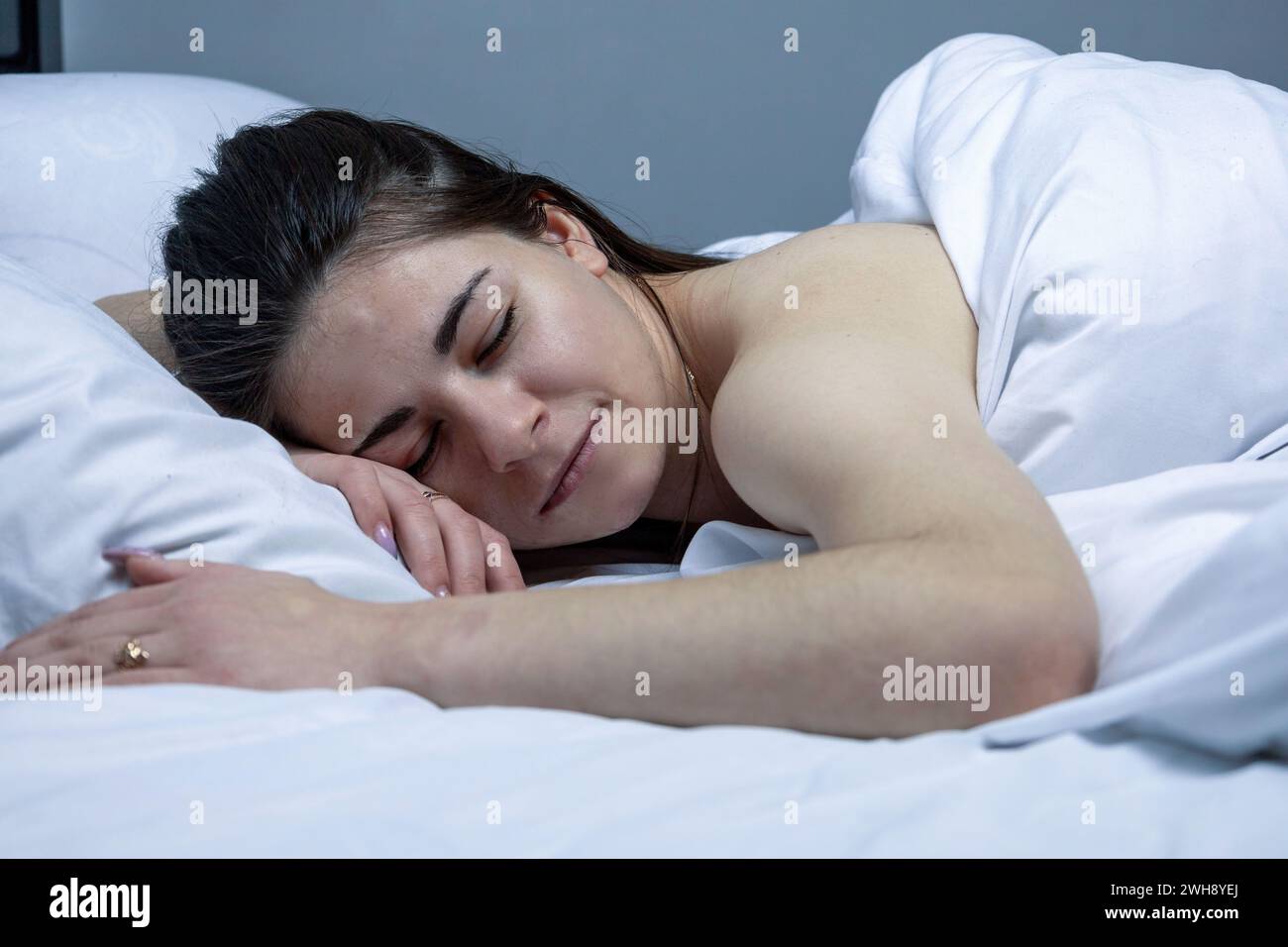 La ragazza dorme in un letto bianco. Foto Stock