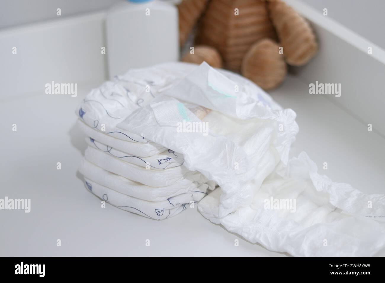Una pila di pannolini, leoni peluche e articoli per bambini sul fasciatoio e nella sala infermieristica Foto Stock