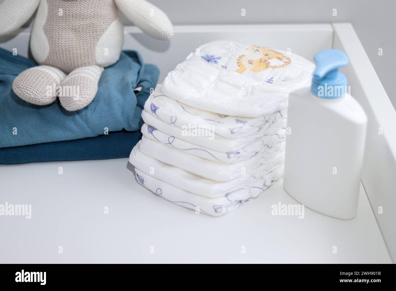 Una pila di pannolini, cipolle blu e articoli per bambini su fasciatoio bianco, sala infermieri Foto Stock