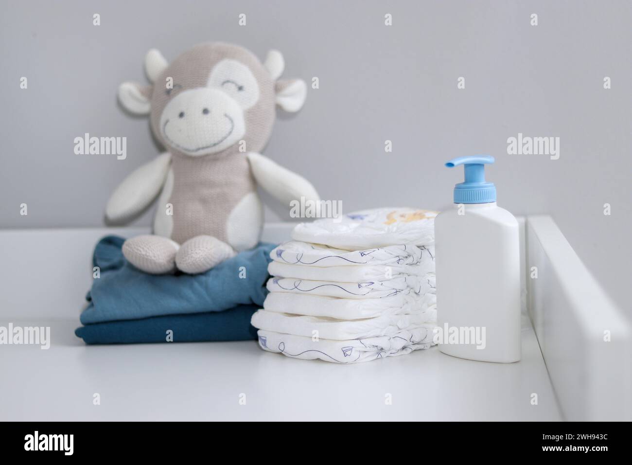 Una pila di pannolini, cipolle blu e articoli per bambini su fasciatoio bianco, sala infermieri Foto Stock