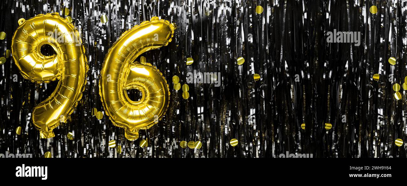Palloncino in lamina d'oro numero 96 su uno sfondo decorato con tinsel nero. Biglietto di auguri di compleanno, iscrizione novantasei. Evento di anniversario Foto Stock