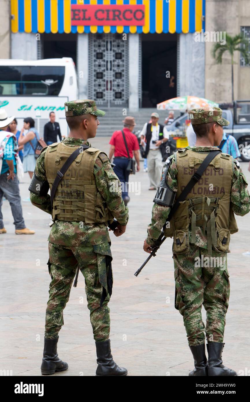 MEDELLIN, COLOMBIA - 14 MARZO: Due militari in piedi sulla piazza con l'arma automatica in mano e persone intorno. Le ultime mostre di El Circo Botero Foto Stock