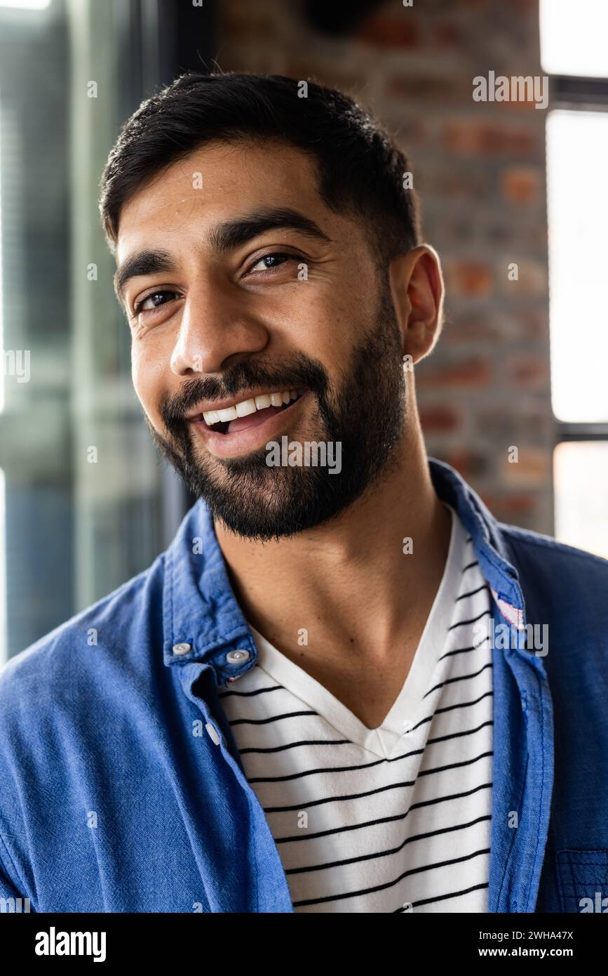 Il giovane uomo asiatico sorride calorosamente in un ambiente informale di ufficio d'affari Foto Stock