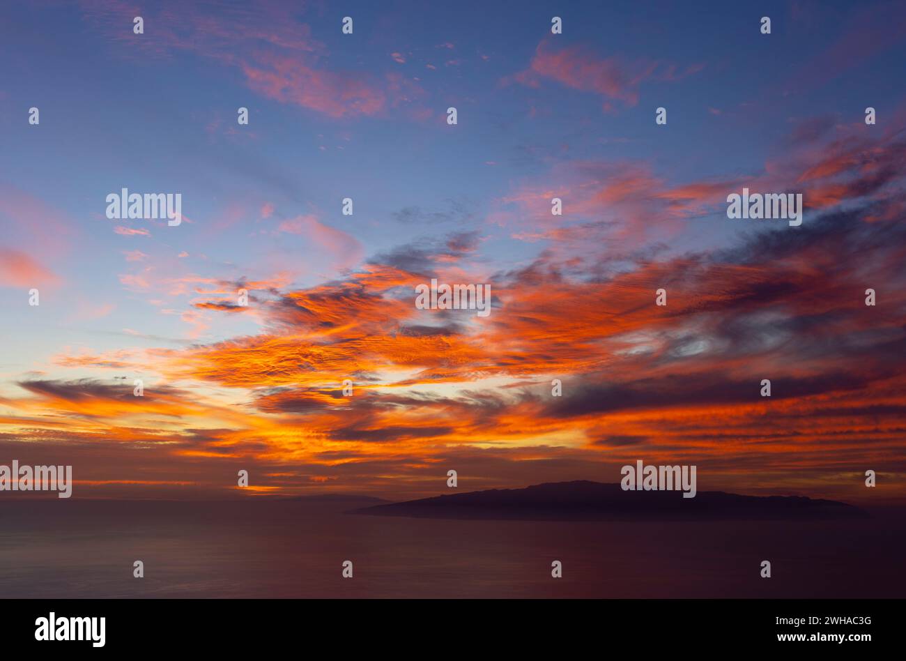 spettacolare tramonto con nuvole rosse e arancioni come pennellate nel cielo blu. spettacolo della natura. il cielo in fiamme Foto Stock
