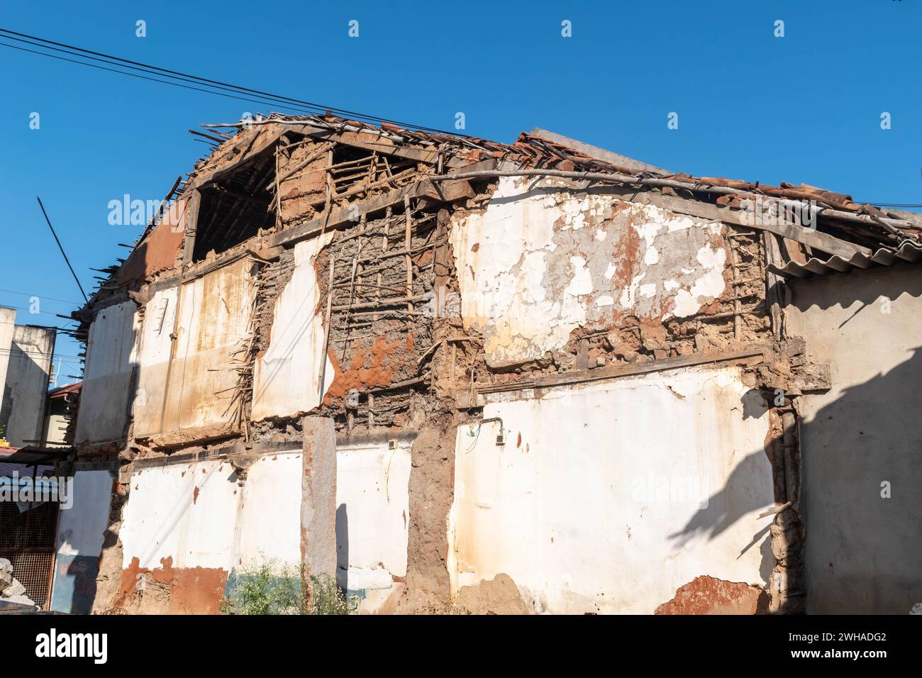Questa immagine cattura le condizioni dure di una struttura a due piani in decadenza con pareti esposte in mezzo a un quartiere urbano. Foto Stock