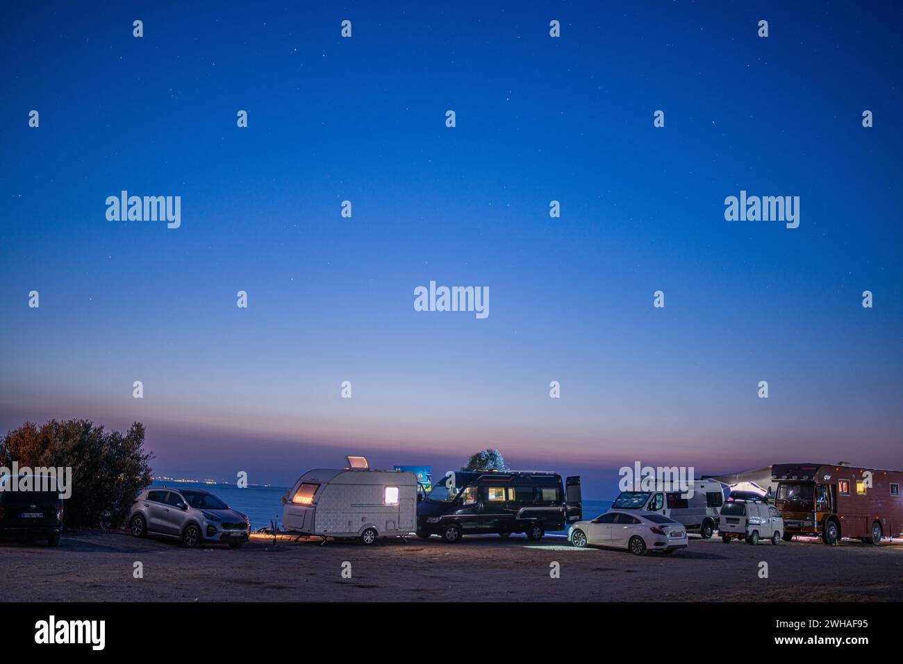 Una vivace scena di camper e furgoni che costeggiano le coste, catturando lo spirito della comunità e dell'avventura nei grandi spazi aperti Foto Stock