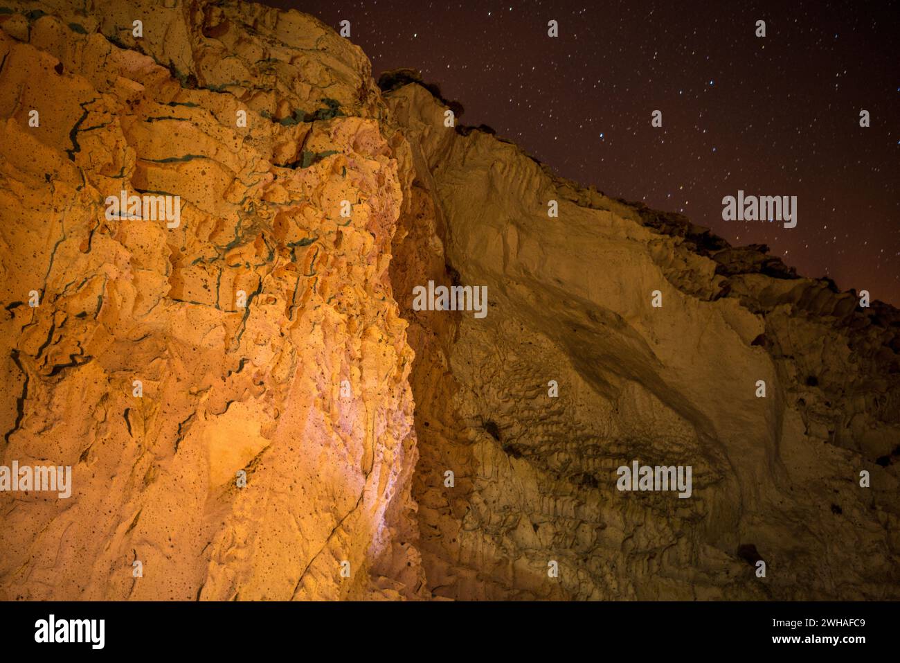 Uno spettacolo celeste si dispiega mentre le stelle adornano il cielo notturno sopra le rocce calcaree delle montagne, creando un panorama cosmico di maestosa bellezza. Foto Stock