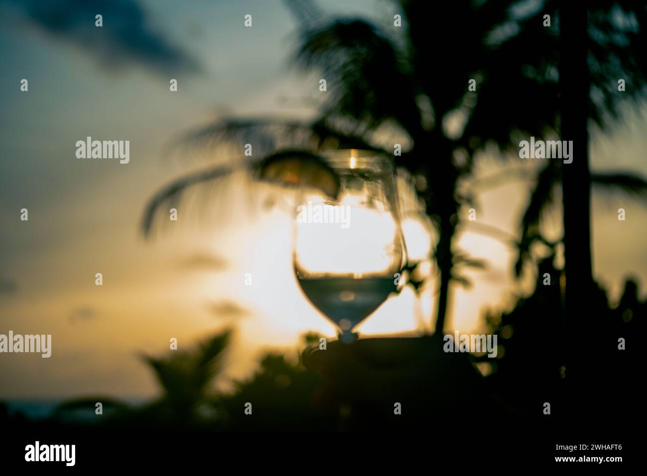 Un momento accattivante sorseggiando un bicchiere da cocktail al tramonto delle Maldive, mescolando sapori esotici con la tranquilla bellezza del paradiso costiero. Foto Stock