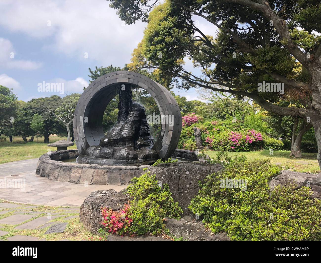 Scultura di roccia vulcanica nel lussureggiante parco verde sull'isola di Jeju Foto Stock