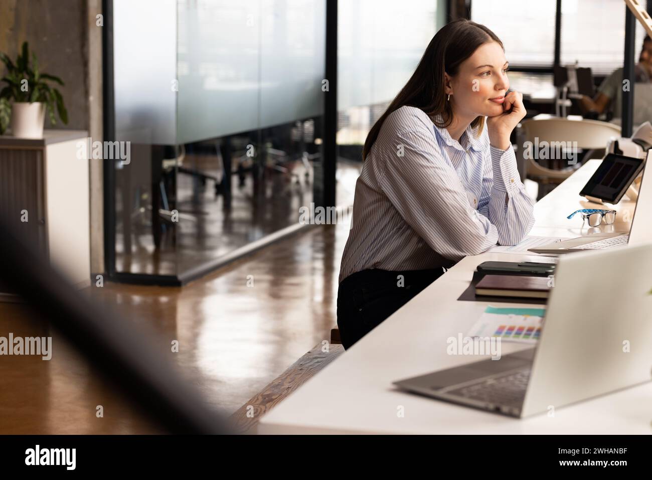 La giovane donna caucasica si siede con cura alla sua scrivania informale Foto Stock