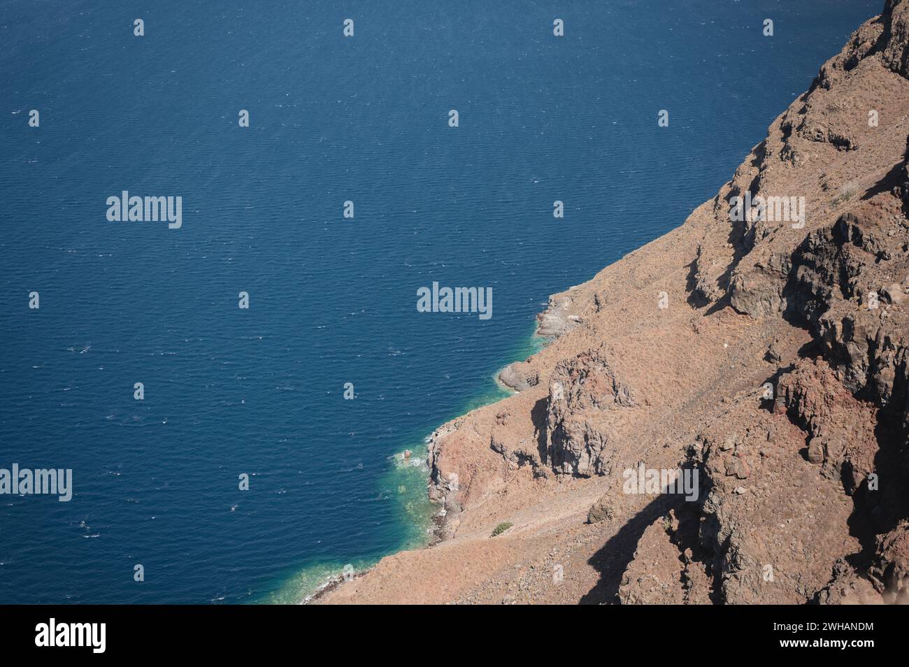 Vista dall'alto dell'acqua di mare che si schianta sulla costa rocciosa di Santorini Foto Stock