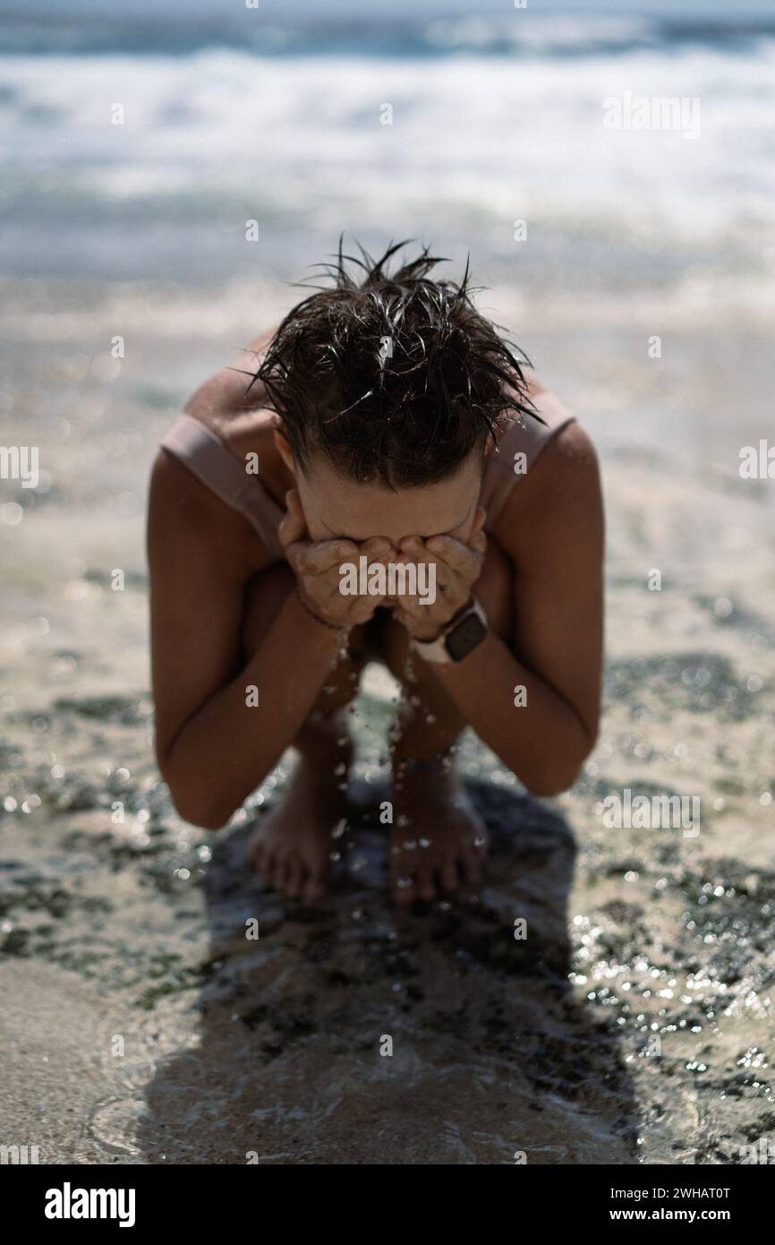 Una giovane donna si bagna nell'oceano e bagna l'acqua salata, in vacanza al mare Foto Stock