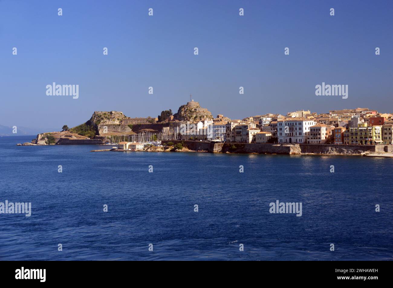 La Fortezza Vecchia e nuova accanto agli edifici e alle case sul lungomare di Corfù città dal mare, Grecia, UE. Foto Stock