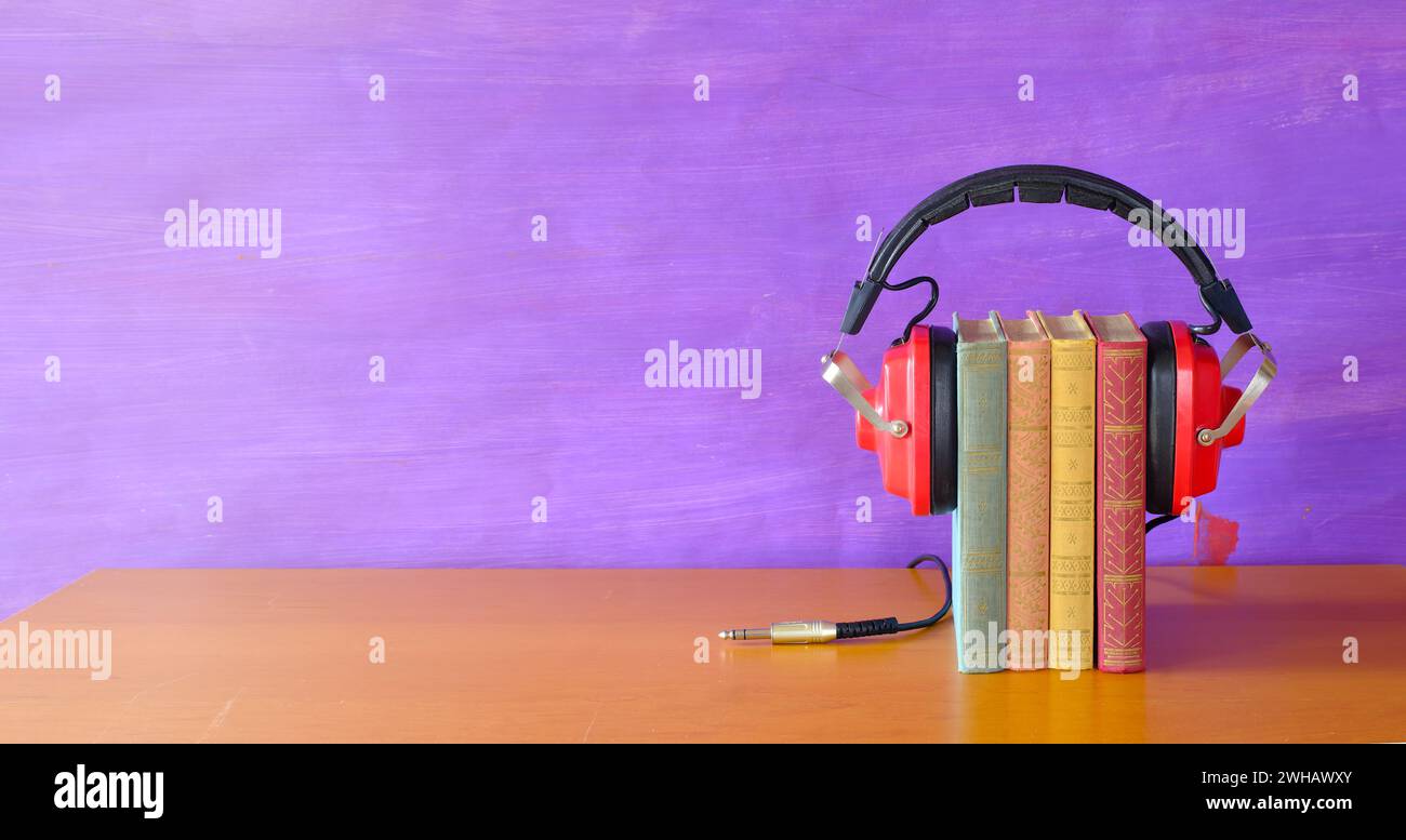 Rilassatevi con il concetto di audiolibri con un mucchio di libri e auricolari vintage. Sfondo con ampio spazio per le copie Foto Stock