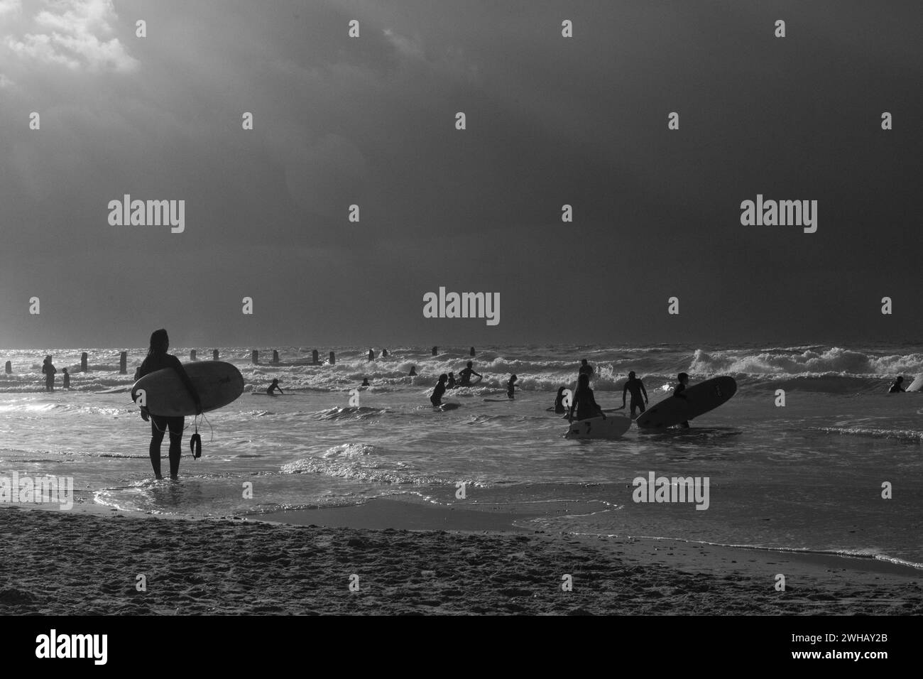 Gli appassionati di sport acquatici con varie forme di surf e vela in bianco e nero al crepuscolo fotografati sulla spiaggia di Beit Yanai, Israel Beit Yanai Foto Stock