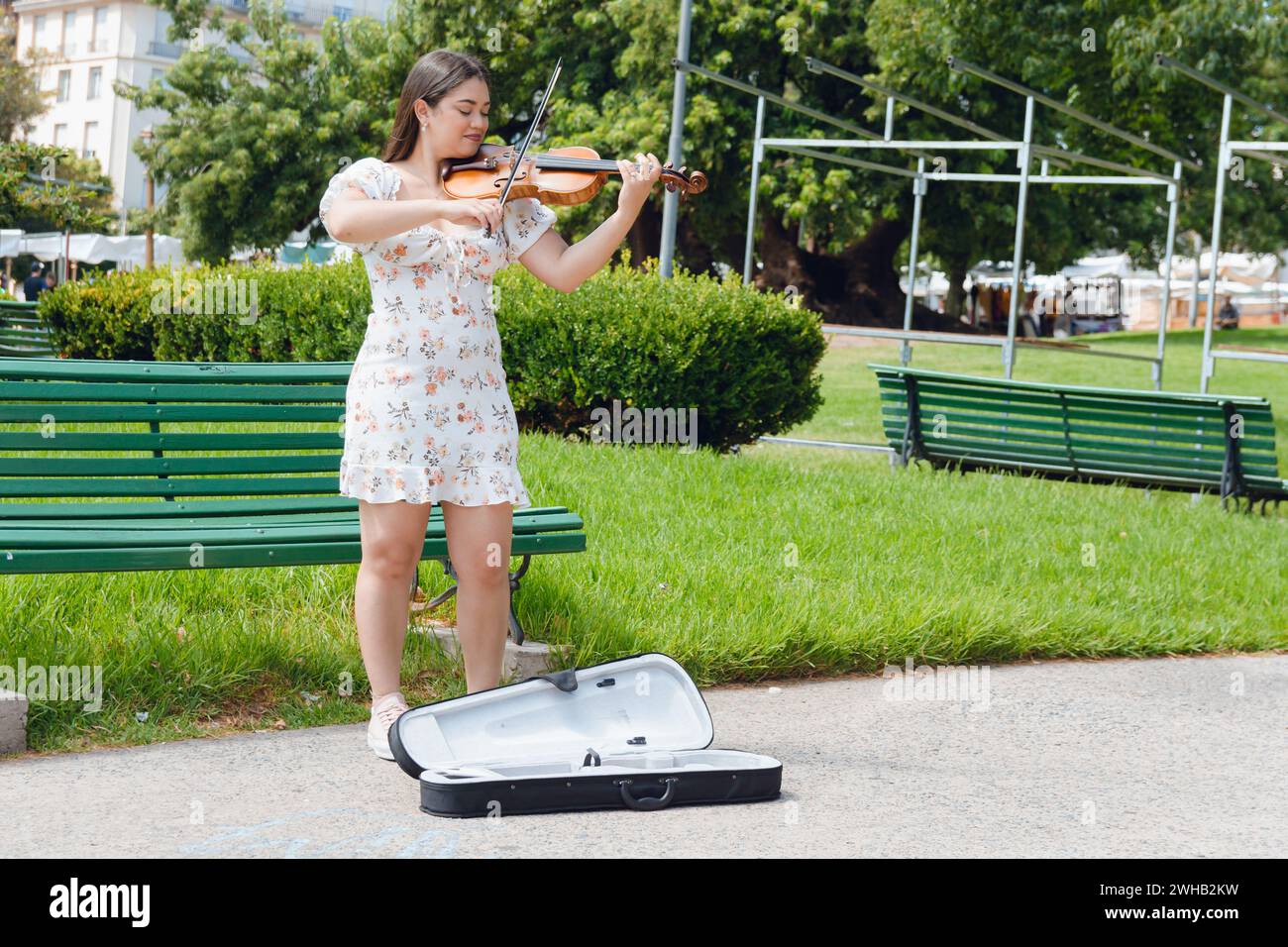 immagine verticale di una giovane donna di busker latina violinista che indossa un abito, capelli lunghi, ha ispirato un felice gioco per strada, facendo musica e lavorando, copiando spazio. Foto Stock