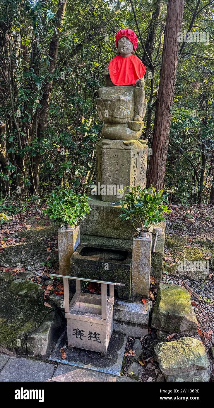 Antica statua adornata con un mantello cremisi, graziosamente arroccata su gradini di pietra Foto Stock