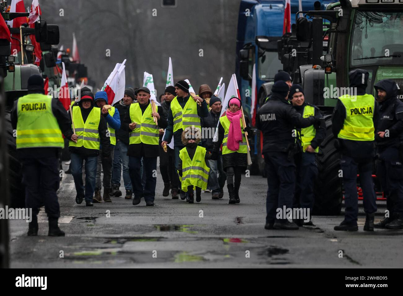 Poznan, Polonia, 9 febbraio 2024. Gli agricoltori della regione della grande Polonia nella Polonia occidentale camminano con le bandiere polacche davanti ai loro trattori mentre bloccano la strada Aleja Niepodleglosci nel centro di Poznań, la capitale della grande Polonia durante lo sciopero degli agricoltori a livello nazionale. La protesta in Polonia fa parte della protesta degli agricoltori europei contro i regolamenti del Green Deal dell'UE. Gli agricoltori polacchi chiedono inoltre una modifica dell'accordo UE con l'Ucraina in merito all'importazione di prodotti agricoli nell'UE. La protesta a Poznań, la capitale della grande Polonia, fu organizzata da Rola Wielkopolska e. Foto Stock