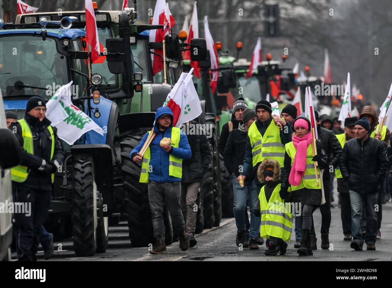 Poznan, Polonia, 9 febbraio 2024. Gli agricoltori della regione della grande Polonia nella Polonia occidentale camminano con le bandiere polacche davanti ai loro trattori mentre bloccano la strada Aleja Niepodleglosci nel centro di Poznań, la capitale della grande Polonia durante lo sciopero degli agricoltori a livello nazionale. La protesta in Polonia fa parte della protesta degli agricoltori europei contro i regolamenti del Green Deal dell'UE. Gli agricoltori polacchi chiedono inoltre una modifica dell'accordo UE con l'Ucraina in merito all'importazione di prodotti agricoli nell'UE. La protesta a Poznań, la capitale della grande Polonia, fu organizzata da Rola Wielkopolska e. Foto Stock