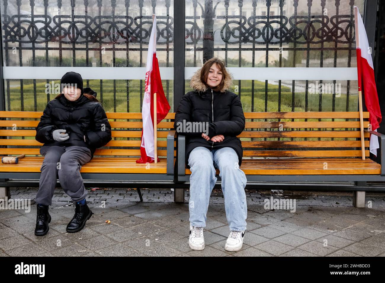 Poznan, Polonia, 9 febbraio 2024. I bambini siedono con le bandiere nazionali polacche su una fermata dell'autobus sulla via Aleja Niepodleglosci nel centro di Poznań, la capitale della grande Polonia durante lo sciopero degli agricoltori a livello nazionale. La protesta in Polonia fa parte della protesta degli agricoltori europei contro i regolamenti del Green Deal dell'UE. Gli agricoltori polacchi chiedono inoltre una modifica dell'accordo UE con l'Ucraina in merito all'importazione di prodotti agricoli nell'UE. La protesta a Poznań, la capitale della grande Polonia, fu organizzata da Rola Wielkopolska e raccolse oltre un migliaio di trattori che bloccarono le strade della città. CRE Foto Stock