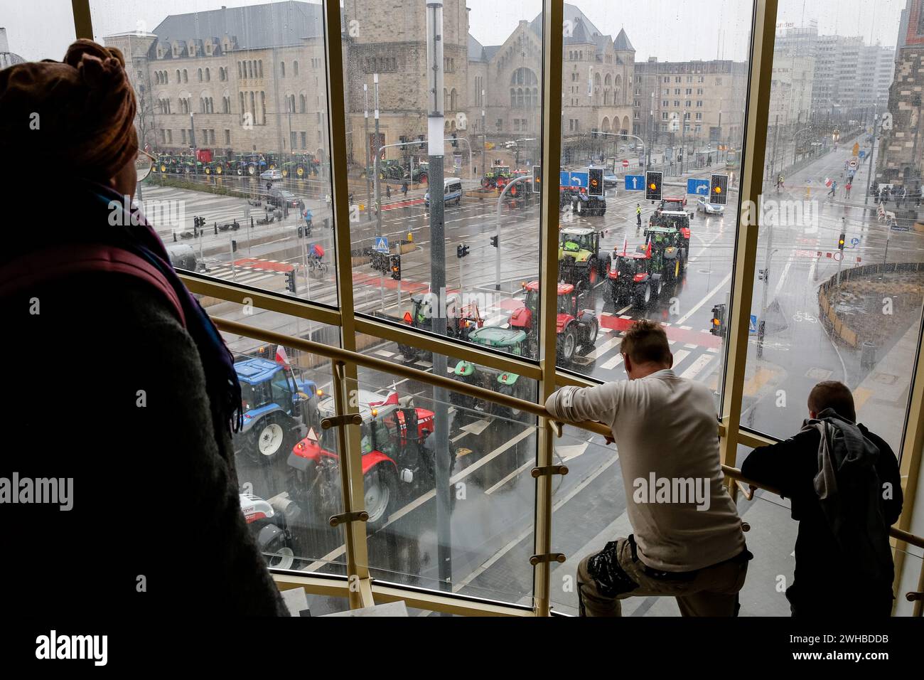 Poznan, Polonia, 9 febbraio 2024. La gente guarda come gli agricoltori della grande Polonia nella Polonia occidentale guidano i loro trattori mentre bloccano la strada Aleja Niepodleglosci nel centro di Poznań, la capitale della grande Polonia durante lo sciopero degli agricoltori a livello nazionale. La protesta in Polonia fa parte della protesta degli agricoltori europei contro i regolamenti del Green Deal dell'UE. Gli agricoltori polacchi chiedono inoltre una modifica dell'accordo UE con l'Ucraina in merito all'importazione di prodotti agricoli nell'UE. La protesta a Poznań, la capitale della grande Polonia, fu organizzata da Rola Wielkopolska e si riunì Foto Stock