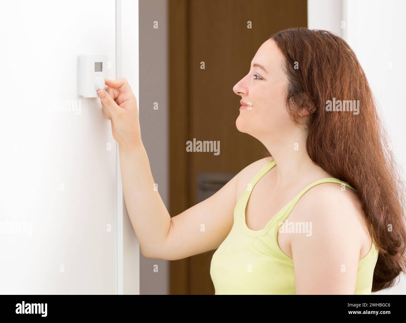 Foto di un ritratto con vista laterale di una bella donna felice con termostato digitale a pulsante in casa Foto Stock