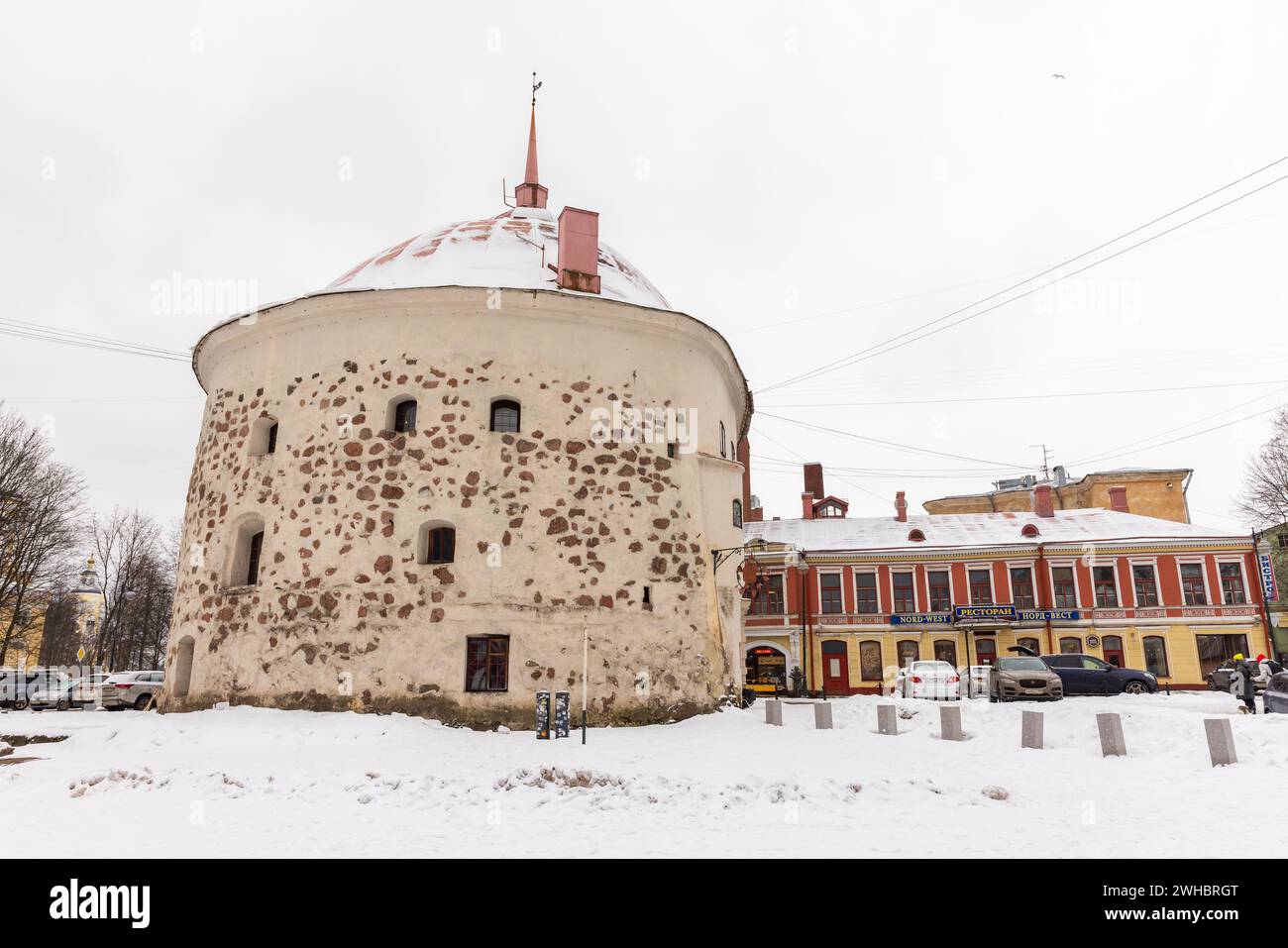Vyborg, Russia - 18 febbraio 2023: Vista sulla strada invernale con l'esterno della torre rotonda dove un arsenale e una prigione erano situati nel vecchio centro Foto Stock