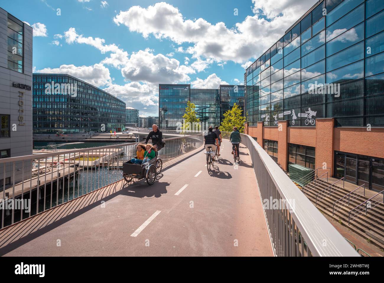 Ponte ciclabile Cykelslangen con ciclisti e 2 bambini su una bicicletta Christiania a Vesterbro, vicino al centro commerciale Fisketorvet Copenhagen a Copenaghen, Danimarca Foto Stock