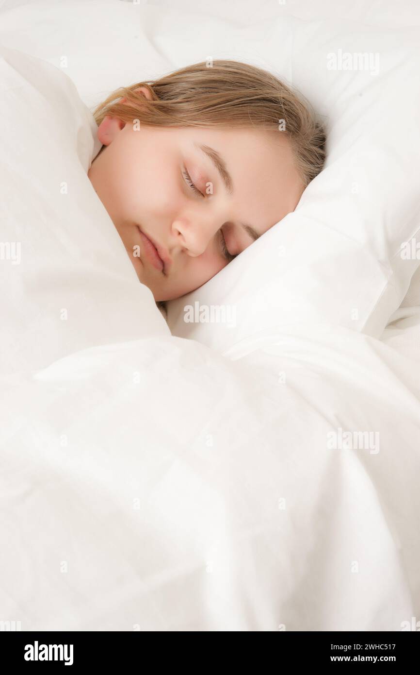 Giovane donna addormentata nel letto Foto Stock