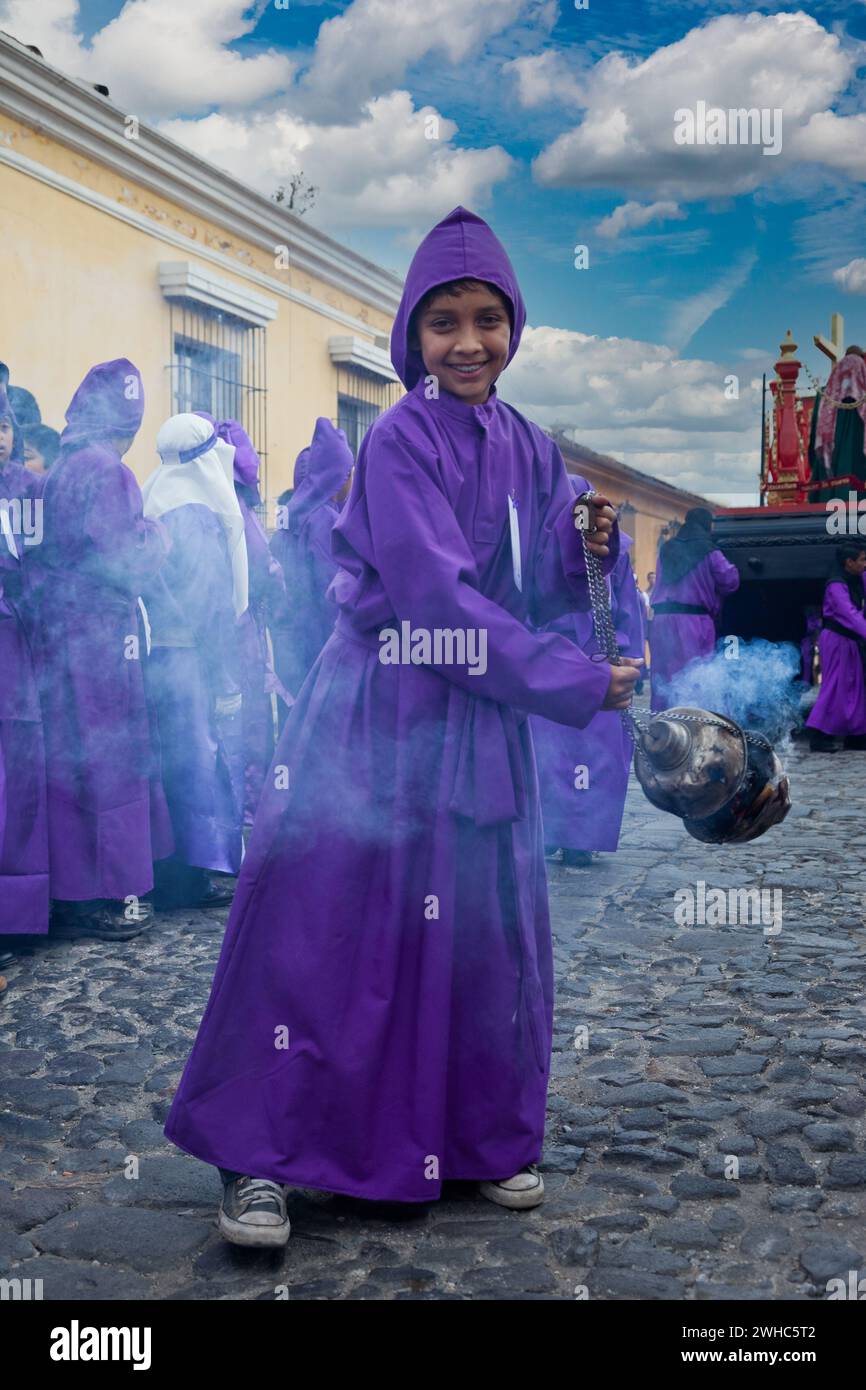 Antigua, Guatemala. Il ragazzo oscilla un Pot Incense mentre precede una Processione religiosa durante il Sacro Weekend, la Semana Santa. Foto Stock