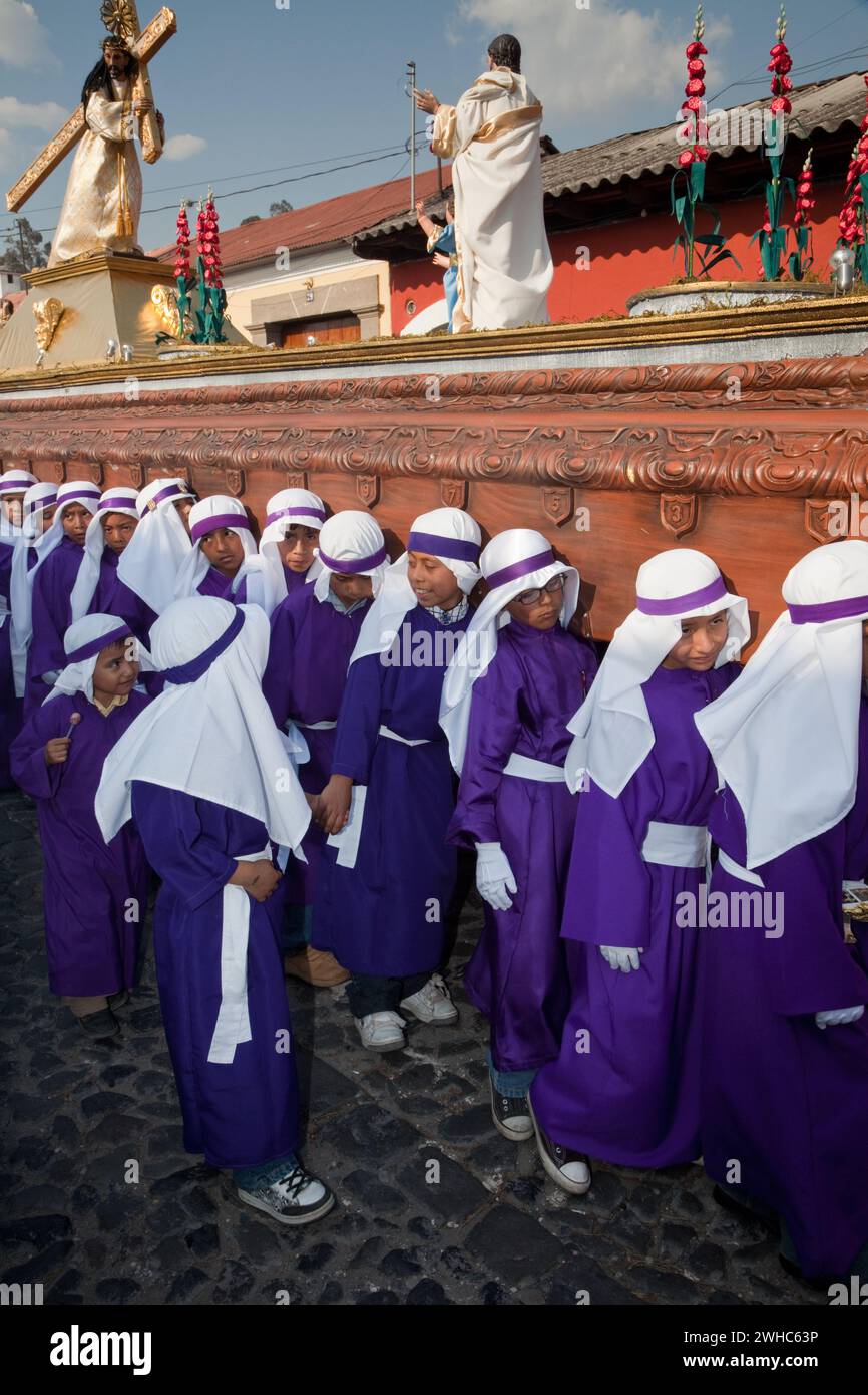 Antigua, Guatemala. Giovani ragazzi che portano un galleggiante in una processione religiosa durante la settimana Santa, la Semana Santa. Foto Stock