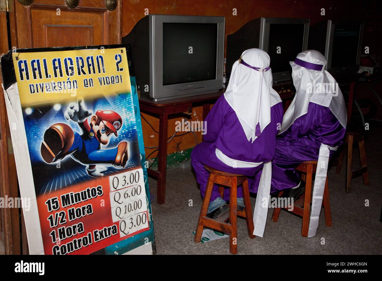Antigua, Guatemala. Due ragazzi giocano a un videogame per rilassarsi dopo aver finito il loro tempo come cucuruchos, trasportando un galleggiante in una delle settimane Santa di Antigua Foto Stock