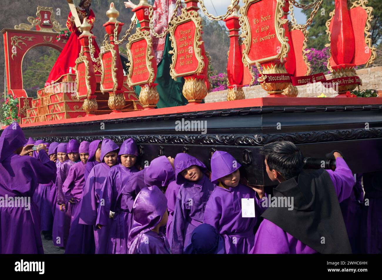 Antigua, Guatemala. Ragazzi adolescenti che portano un galleggiante (Anda) in una Processione religiosa durante la settimana Santa, la Semana Santa. Foto Stock