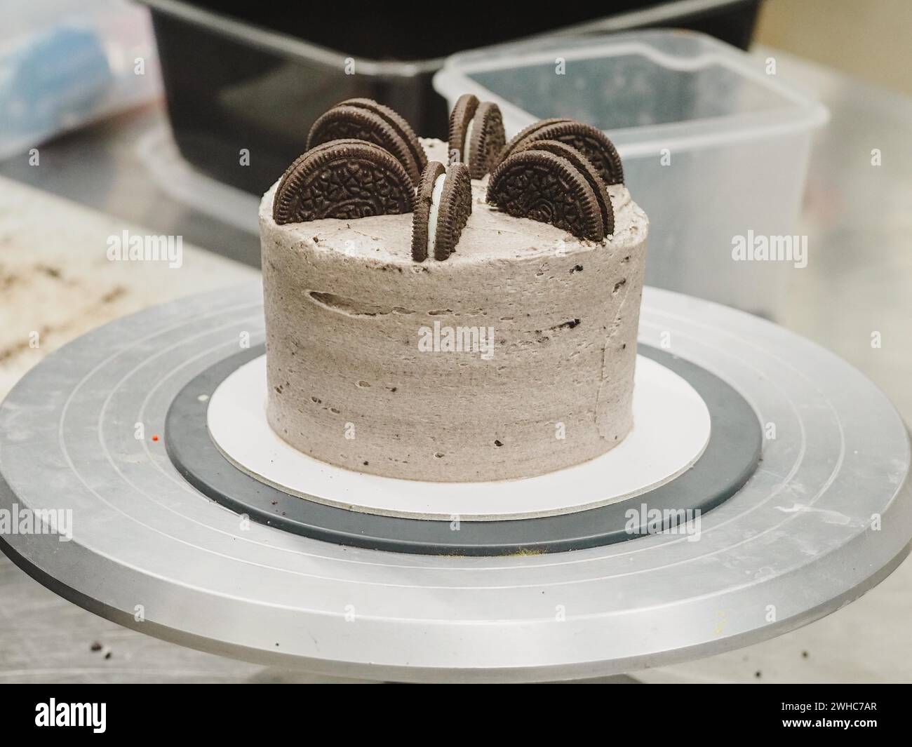 Biscotti al cioccolato fondente che condono una torta con Oreo intere sopra, su un tavolo girevole della cucina Foto Stock