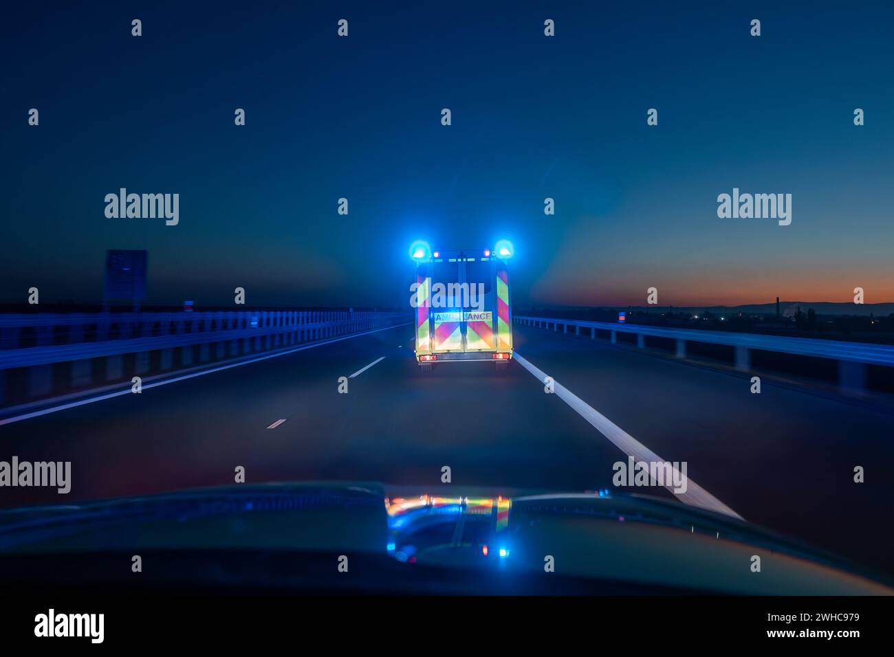 Auto ambulanza veloce in movimento di servizio medico di emergenza su autostrada di notte. Temi assistenza sanitaria, soccorso e urgenza. Foto Stock