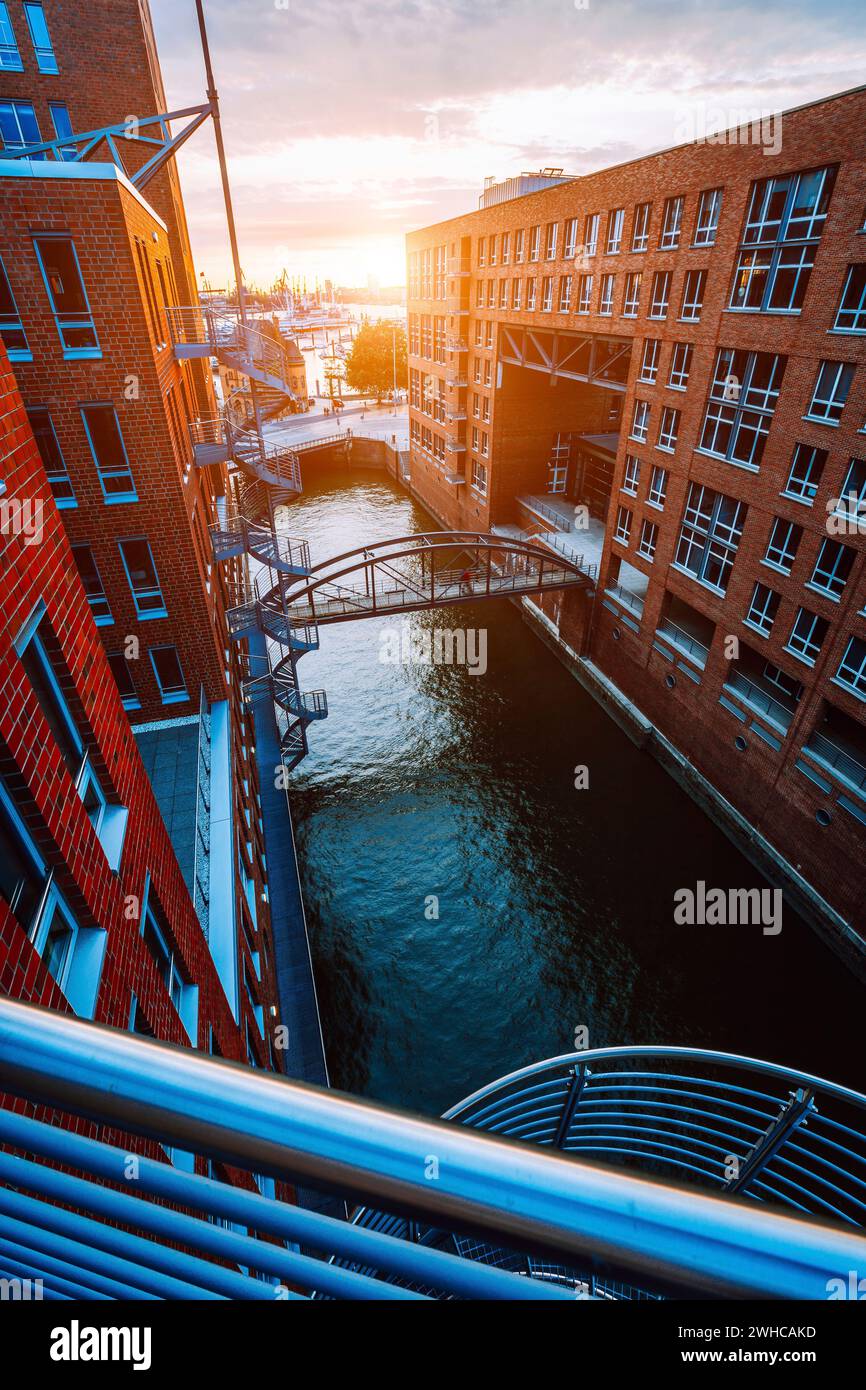 Scala metallica, ponte sul canale e edifici in mattoni rossi nel vecchio quartiere dei magazzini Speicherstadt ad Amburgo, all'ora d'oro del tramonto, Germania. Vista dall'alto. Foto Stock
