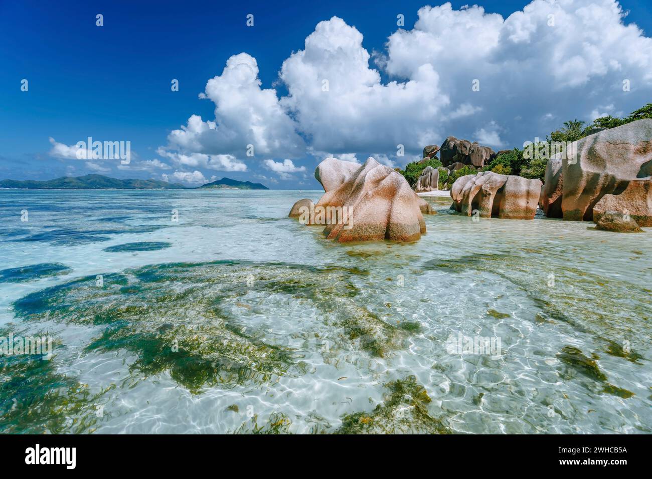 Anse Source d'Argent nella bassa marea - Spiaggia tropicale Paradiso con laguna blu poco profonda, massi di granito e nuvole bianche sopra. Isola di la Digue, Seychelles. Foto Stock