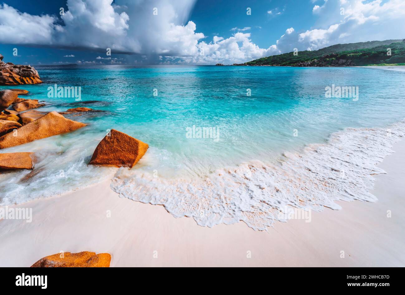 Dolce onda di schiuma sulla spiaggia di Grand Anse, la Digue, Seychelles. Nuvole bianche, mare cristallino, scenario di vacanza. Foto Stock