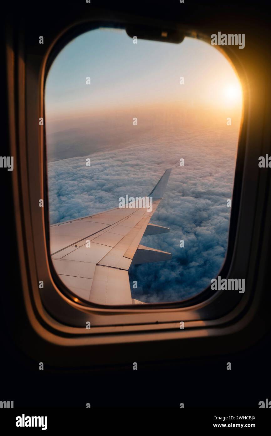 Volo serale in aereo nel cielo crepuscolo. Vista del tramonto nel telaio del finestrino congelato della cabina. Foto Stock