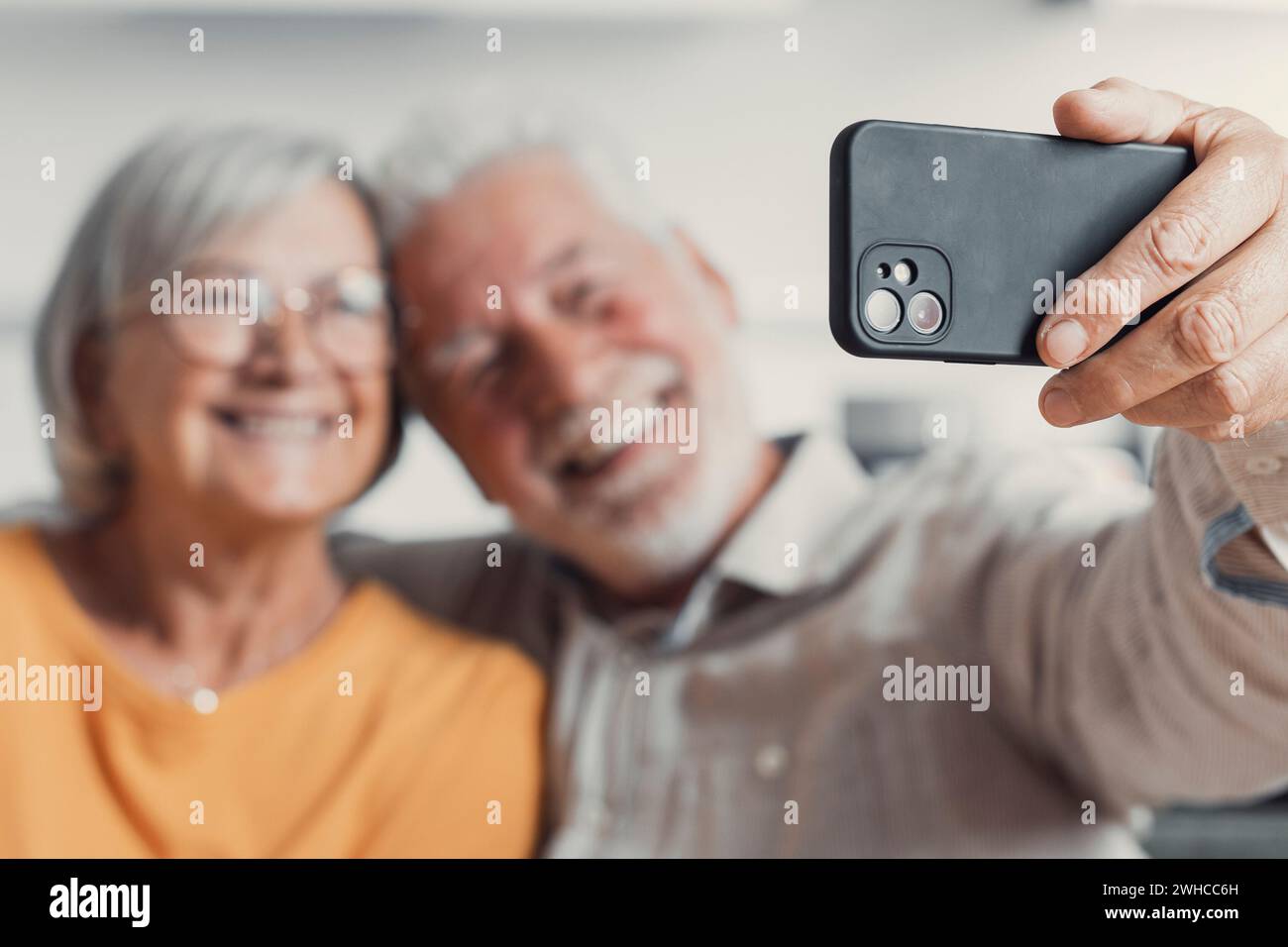 Una vecchia coppia felice che scatta selfie al cellulare, sposi anziani e maturi sorridenti, moglie di mezza età e marito in pensione che ridono tenendo il telefono, realizza un autoritratto sulla fotocamera dello smartphone, concentrandoti sul display del cellulare Foto Stock