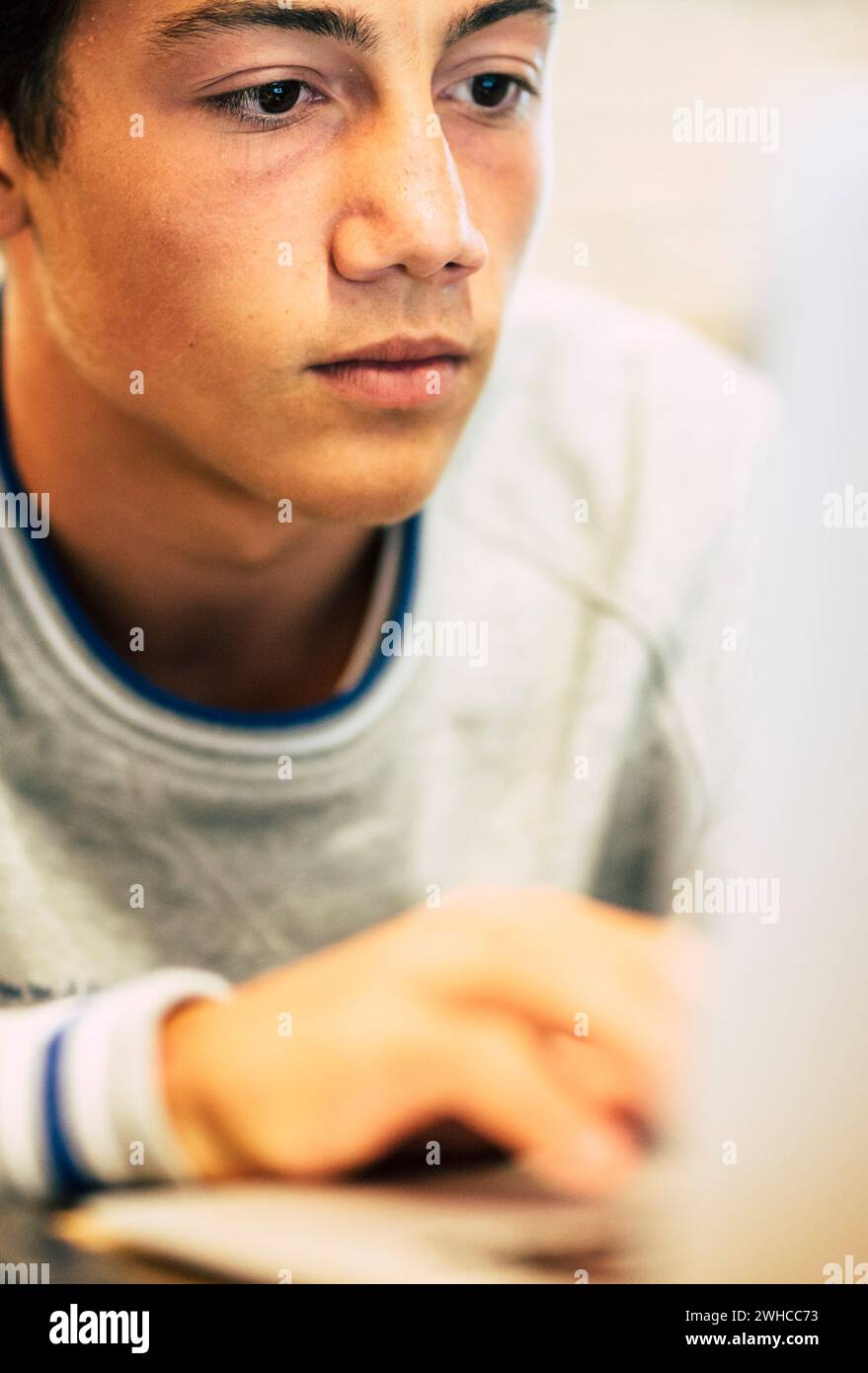 ritratto di un adolescente a casa utilizzando il suo computer portatile per guardare video o giochi: un uomo che lavora al office con il suo computer Foto Stock