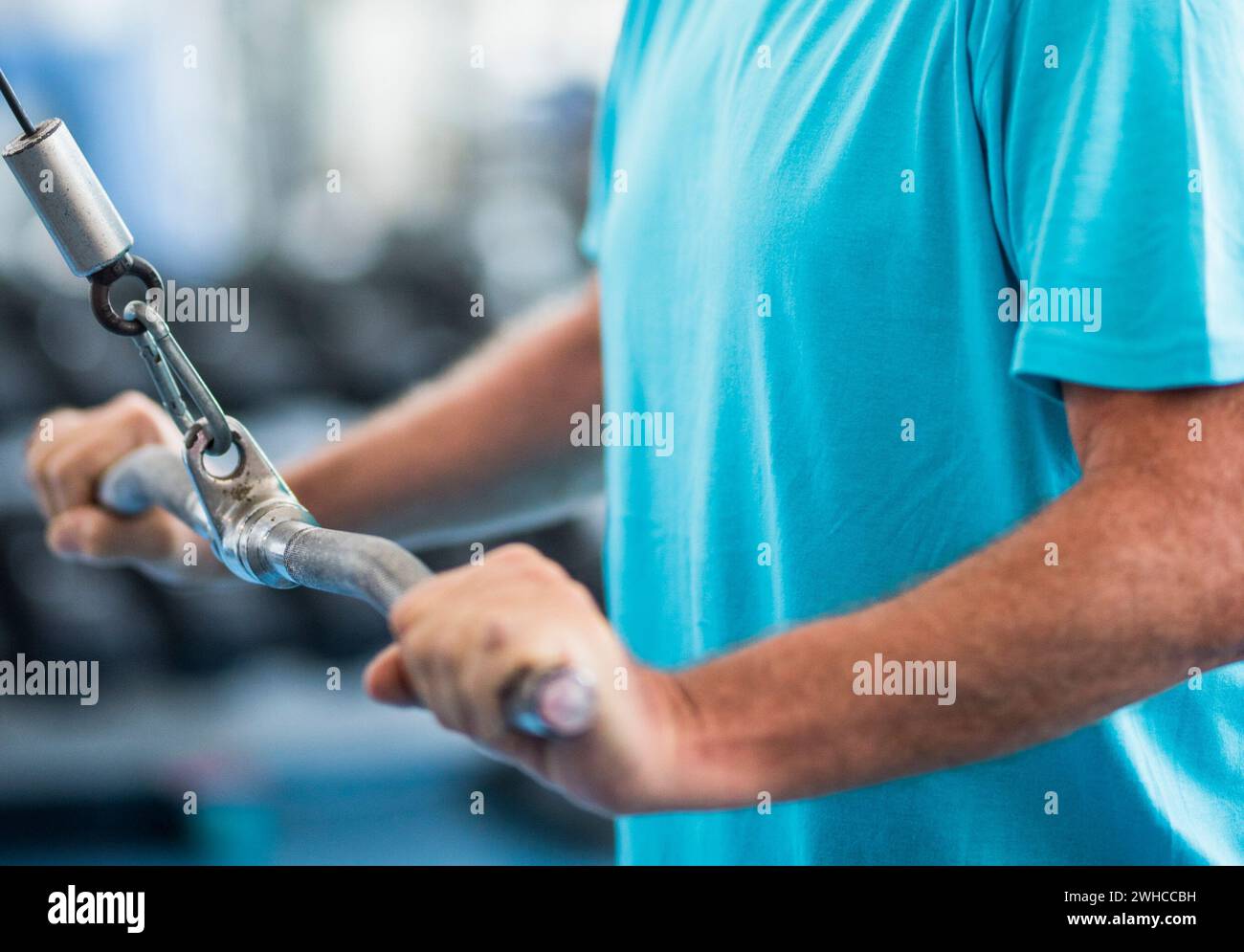 un uomo maturo che solleva un peso con una macchina in palestra - allenamento senior attivo duro da solo - uomo sano e fitness Foto Stock