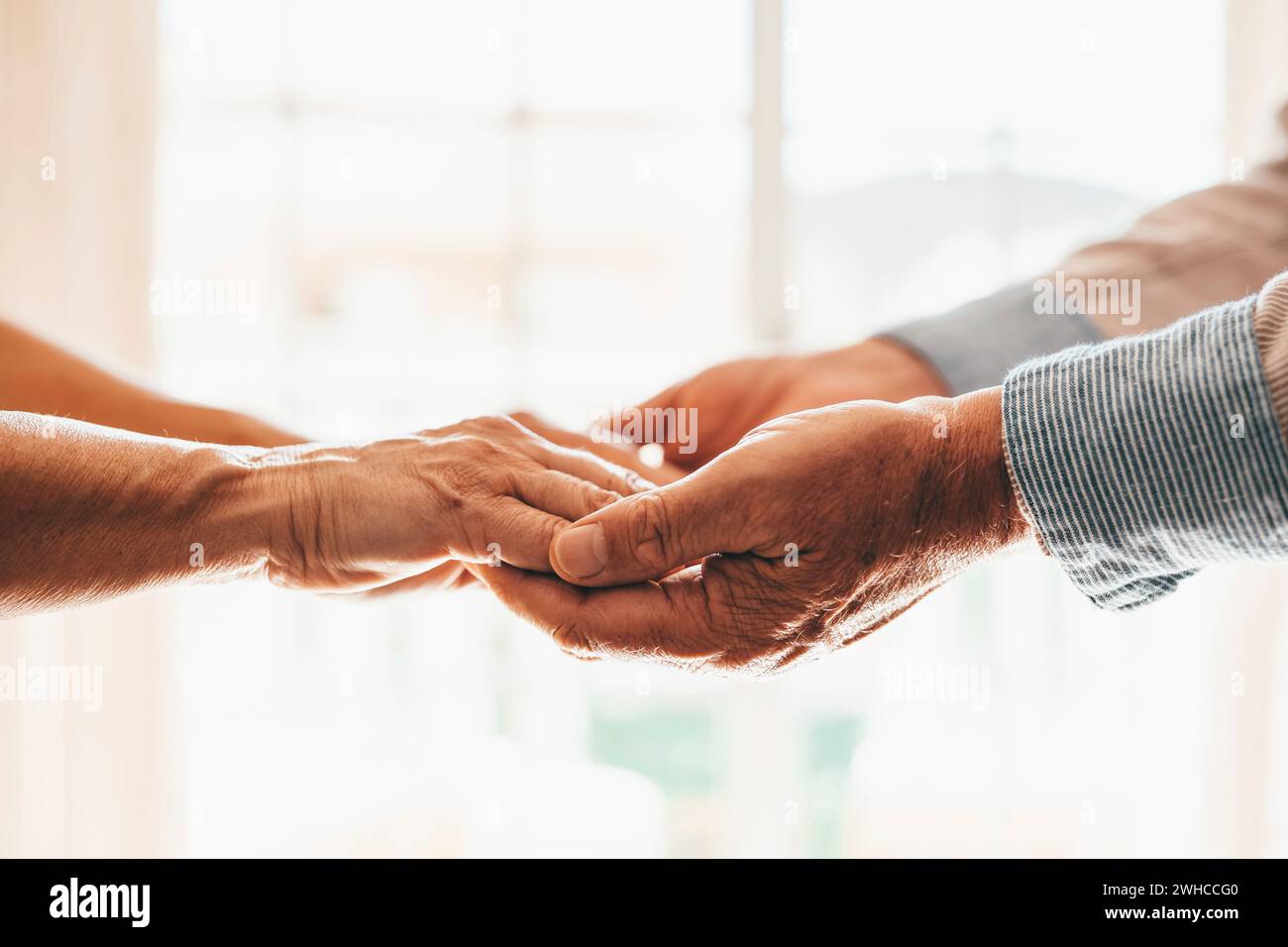 Primo piano donna affettuosa anziana che copre le mani rugose di marito maturo, mostrando amore e sostegno a casa. Una coppia di famiglia di mezza età che si prende cura di una conversazione sincera, fiduciosa e onesta. Foto Stock