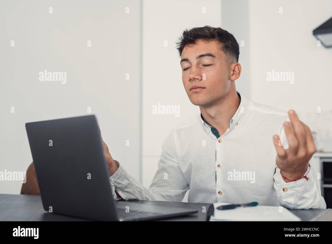 Dipendente di sesso maschile seduto alla scrivania rilassarsi facendo yoga, pratica la meditazione per ridurre lo stress alleviare la fatica sentire l'equilibrio interno sul posto di lavoro, migliorare la consapevolezza, mantenere il concetto di salute mentale Foto Stock