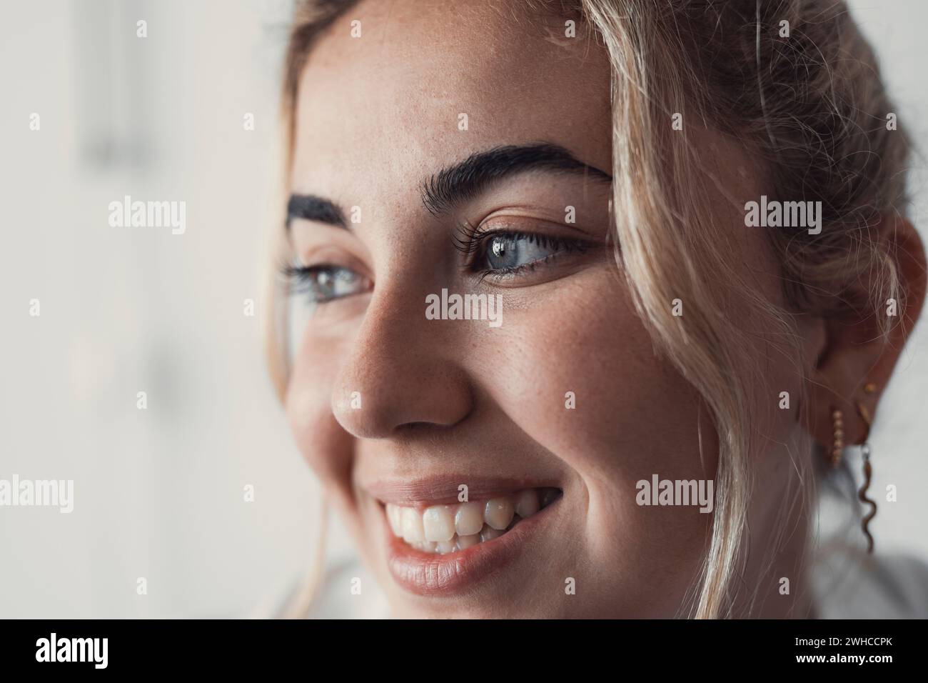 Parte ravvicinata ritagliata del volto femminile, giovane donna caucasica felice ritratto guardare da parte, con un sorriso dalla dentatura bianca, rughe intorno agli occhi, fissare in lontananza. Bellezza naturale, trattamenti per la cura della pelle Foto Stock